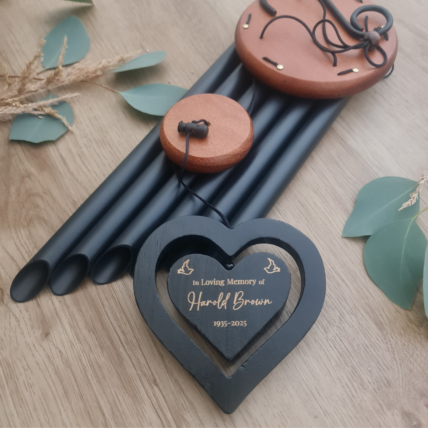 Memorial wind chime with heart-shaped plaque on a wooden surface